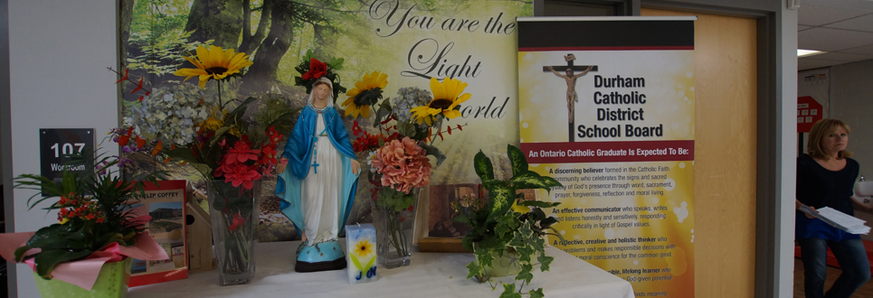 Monsignor Philip Coffey alter with flowers and statue of Mary with stand up banner stating the Catholic Graduate Expectations.